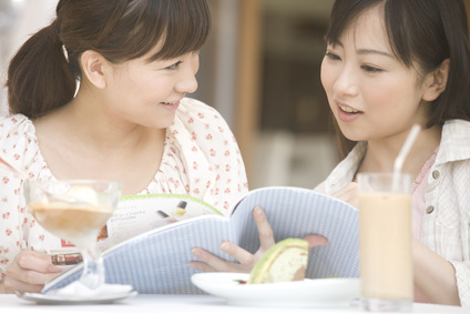 オープンカフェで雑誌を読む2人の女性